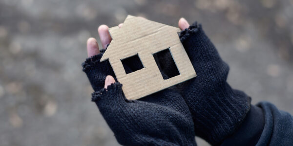 young homeless boy holding a cardboard house